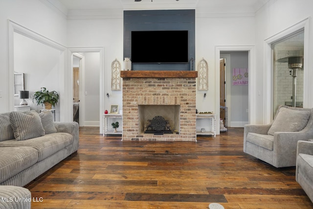 living room with ornamental molding, a brick fireplace, and dark hardwood / wood-style flooring