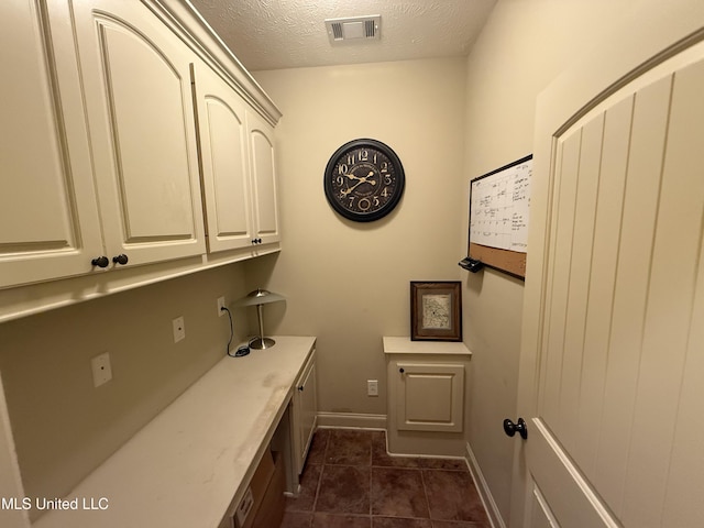 104 Belle Oak Dr, Brandon, MS 39042 - laundry room featuring a textured ceiling, dark tile patterned flooring, and baseboards