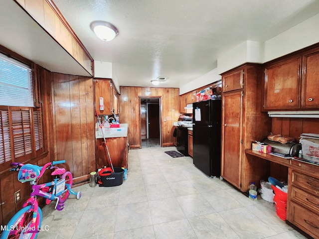 kitchen with black appliances, wood walls, and a textured ceiling