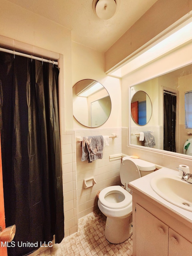 bathroom featuring vanity, toilet, and tile walls