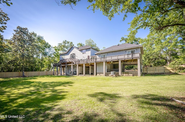 rear view of property with a wooden deck, fence, and a lawn