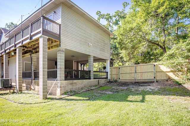 exterior space featuring a lawn, fence, central AC unit, a wooden deck, and a gate
