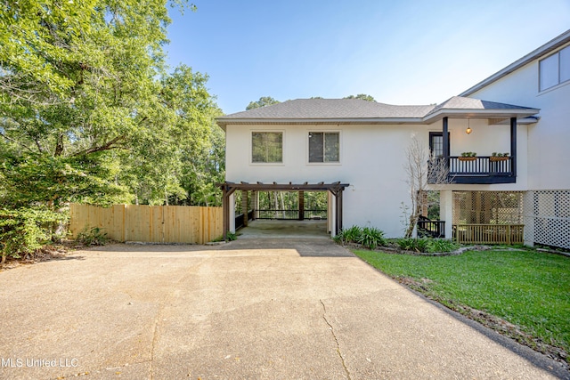 view of front facade featuring driveway, stucco siding, a front yard, and fence