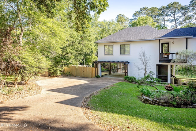 exterior space with stucco siding, fence, a carport, a shingled roof, and driveway