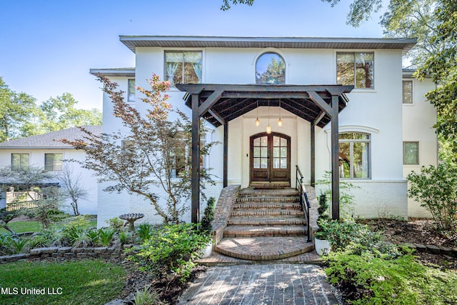 view of front of property featuring brick siding, stucco siding, and french doors