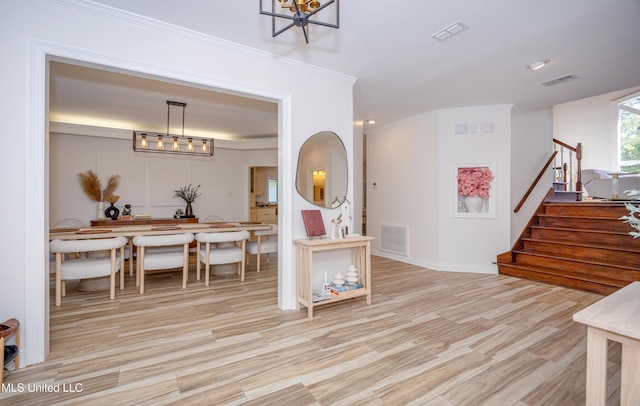 foyer with crown molding, stairs, visible vents, and wood finished floors