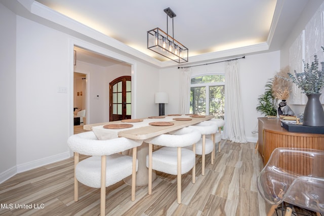 dining room featuring a tray ceiling, baseboards, french doors, and light wood-style floors