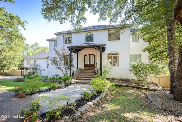 view of front of property with stucco siding, french doors, and fence