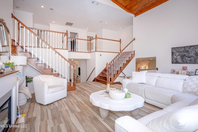 living area with wood finished floors, visible vents, recessed lighting, stairway, and a high ceiling