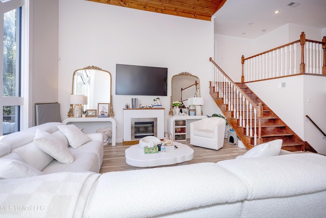 living room featuring stairway, recessed lighting, a glass covered fireplace, and wood finished floors