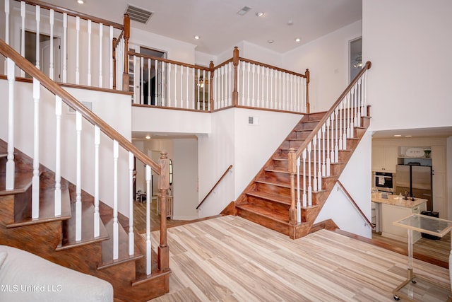 stairway with visible vents, ornamental molding, and recessed lighting
