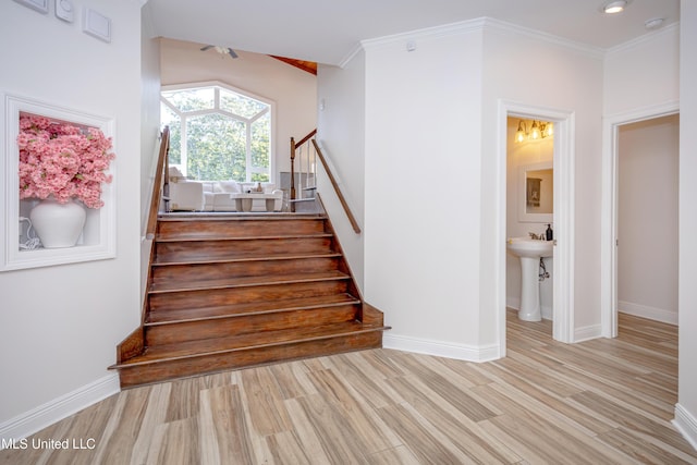 stairway with baseboards, ornamental molding, ceiling fan, and wood finished floors