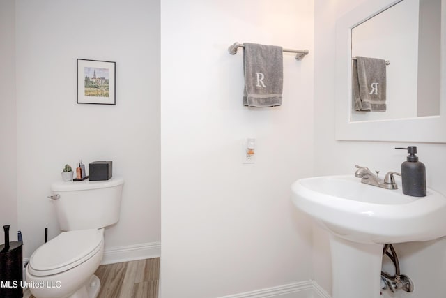 bathroom featuring a sink, toilet, baseboards, and wood finished floors