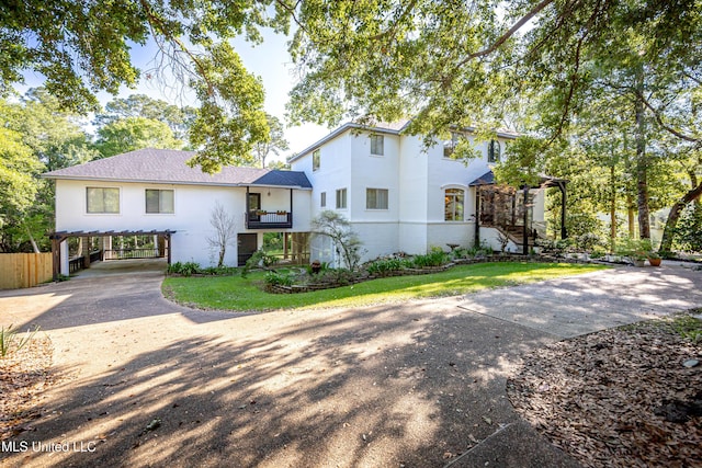view of front of house featuring driveway, fence, stairs, stucco siding, and a carport