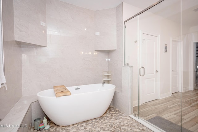 full bath featuring tile walls, a shower stall, visible vents, and a freestanding bath