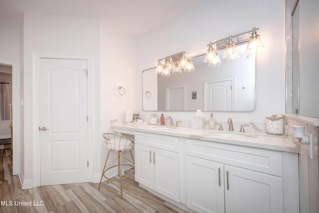 bathroom with a chandelier, double vanity, a sink, and wood finished floors