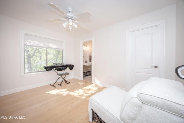 bedroom featuring light wood finished floors, connected bathroom, baseboards, and a ceiling fan