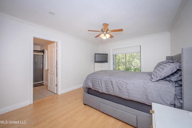 bedroom featuring wood finished floors, crown molding, ensuite bathroom, baseboards, and ceiling fan