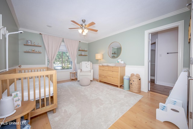 bedroom featuring ornamental molding, a crib, and wood finished floors