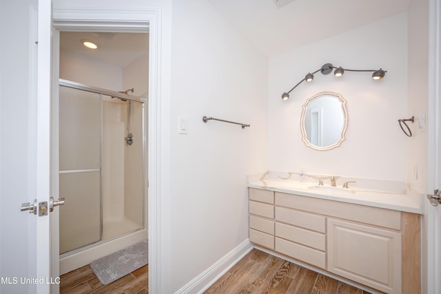 full bathroom featuring a stall shower, baseboards, vanity, and wood finished floors