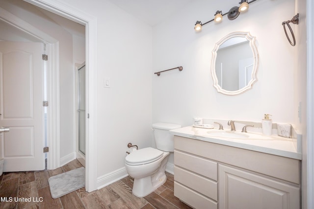 full bathroom with toilet, wood finished floors, baseboards, a shower stall, and vanity