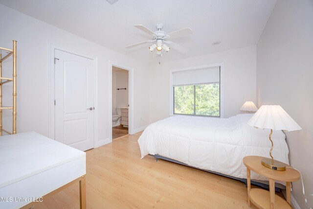 bedroom with light wood finished floors, ensuite bath, baseboards, and a ceiling fan