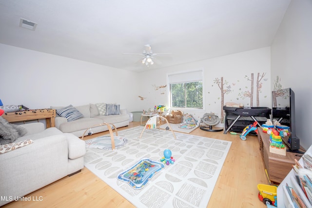 living room with ceiling fan, visible vents, and wood finished floors