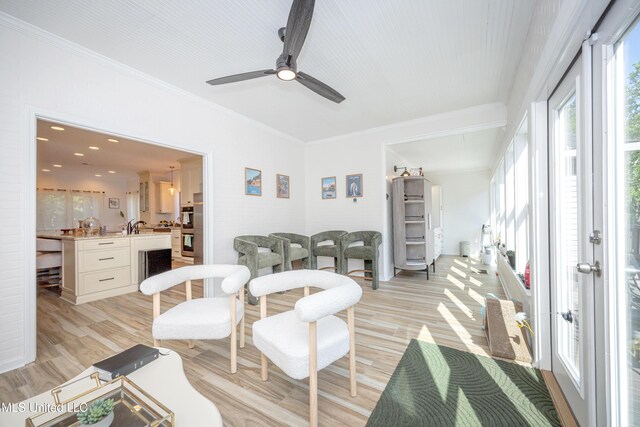living room featuring a ceiling fan, light wood-style floors, and crown molding