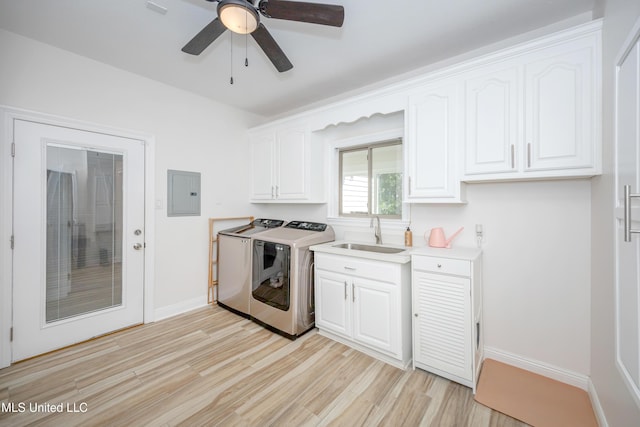 clothes washing area with light wood-style flooring, independent washer and dryer, a sink, electric panel, and cabinet space