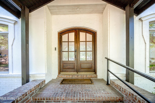 view of exterior entry featuring stucco siding and french doors