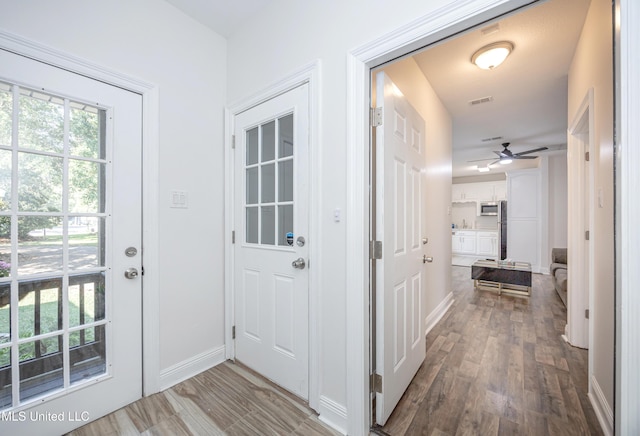 doorway to outside featuring a wealth of natural light, visible vents, wood finished floors, and ceiling fan