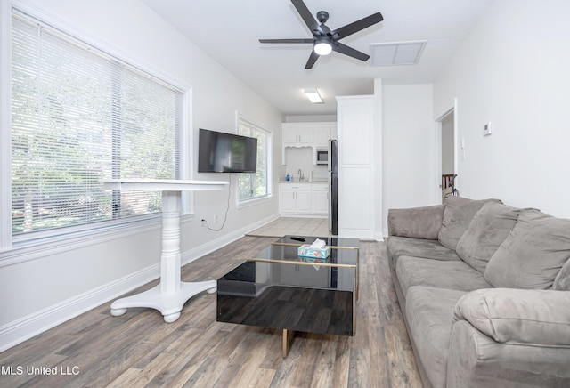 living room with baseboards, a ceiling fan, visible vents, and light wood-style floors