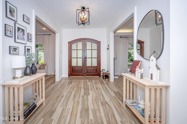 foyer entrance featuring ornamental molding, a healthy amount of sunlight, french doors, and an inviting chandelier