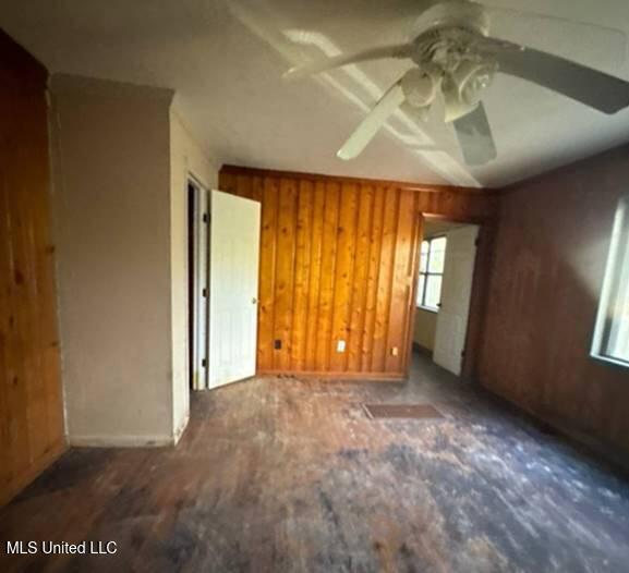 spare room with ceiling fan and wood walls