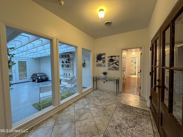 hall with light tile patterned flooring and a textured ceiling