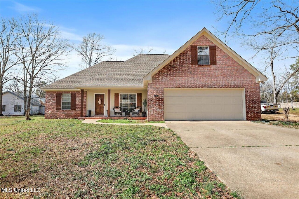 view of front of home featuring a garage, a front yard, and covered porch