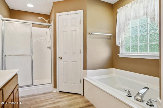 bathroom featuring vanity, independent shower and bath, and wood-type flooring