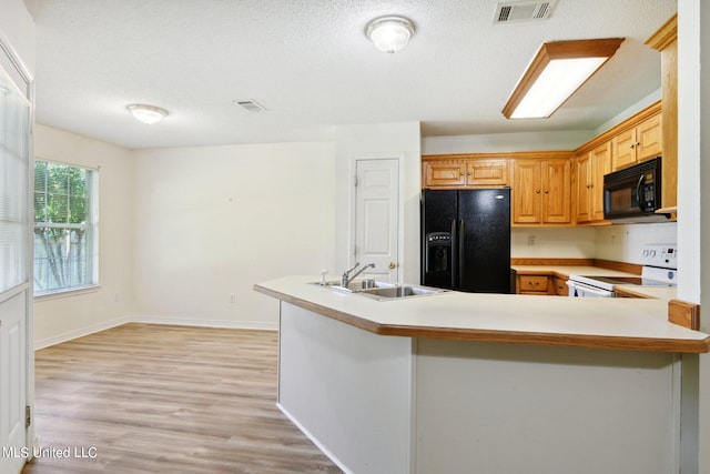 kitchen featuring black appliances, sink, a textured ceiling, kitchen peninsula, and light hardwood / wood-style floors