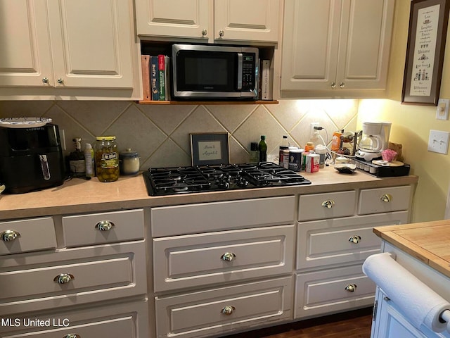 kitchen with black gas stovetop, white cabinetry, and dark hardwood / wood-style flooring