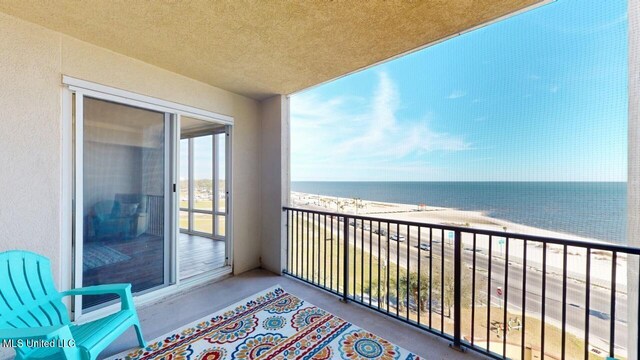 balcony with a water view and a view of the beach