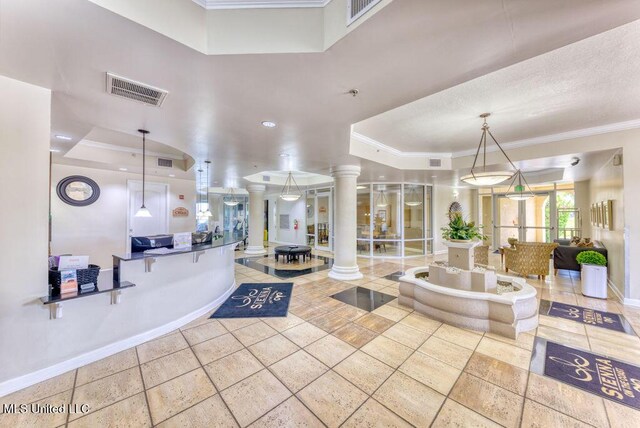 interior space featuring ornamental molding, a raised ceiling, decorative columns, and baseboards