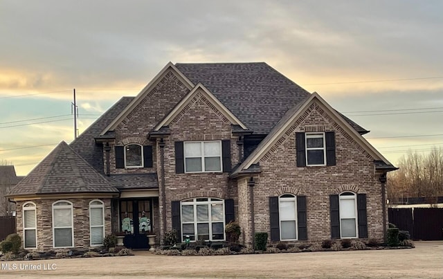 view of front of home featuring brick siding, a lawn, and a shingled roof