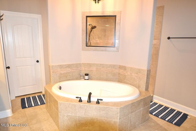 bathroom featuring tile patterned flooring, baseboards, and a bath