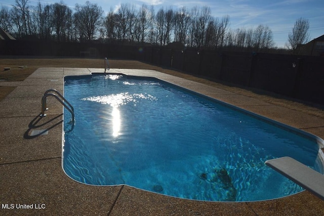 outdoor pool with a diving board, a patio, and a fenced backyard