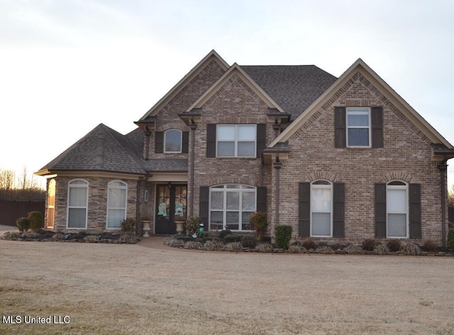 view of front of house featuring roof with shingles, a front yard, and brick siding