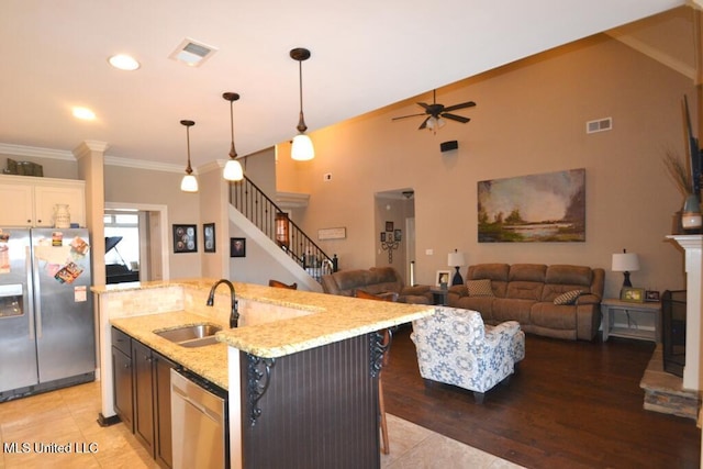 kitchen with a sink, visible vents, appliances with stainless steel finishes, a center island with sink, and pendant lighting