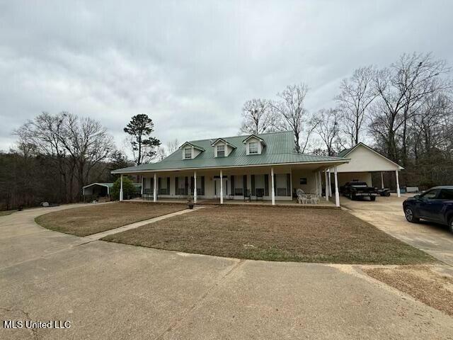 country-style home with covered porch, concrete driveway, a carport, and metal roof