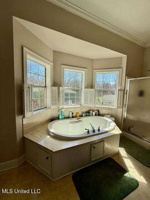 bathroom with a whirlpool tub, a stall shower, baseboards, and ornamental molding