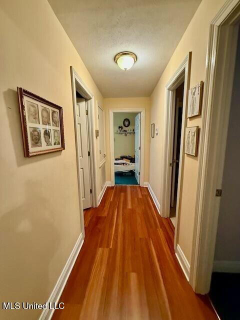 hall featuring baseboards and dark wood-style flooring