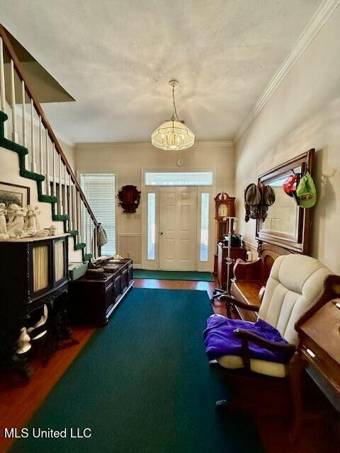 entrance foyer featuring crown molding, stairway, and wood finished floors